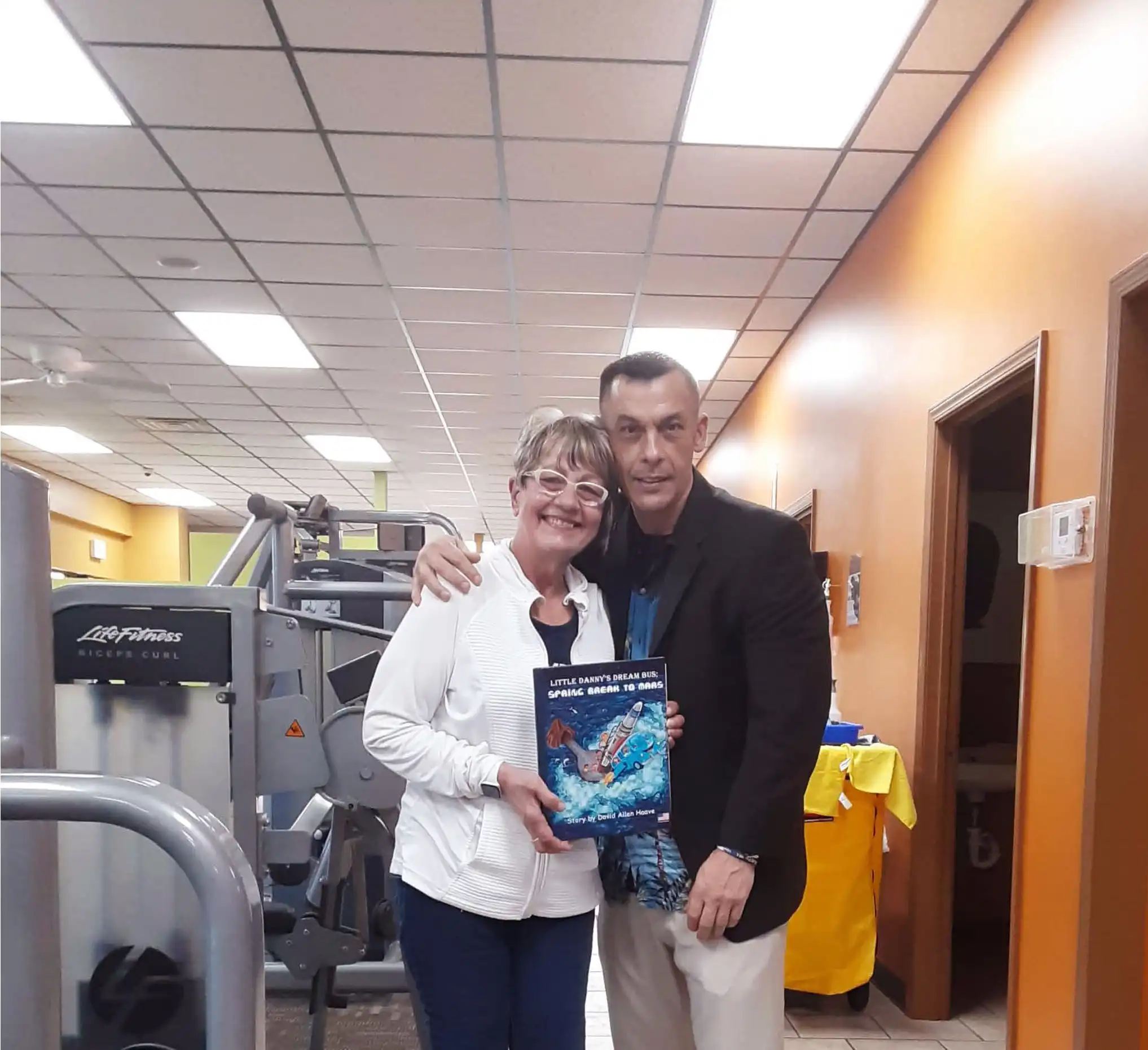Working out in Missouri, author David Haave gets his books signed from gym members dedicating books to Texas Children's Hospital.